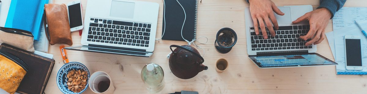 a crowded desk as a person works on a laptop