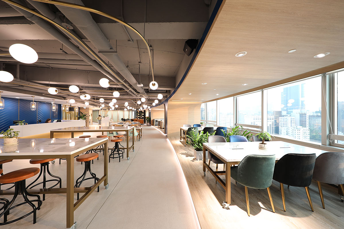 A two tiered co-working space with large floor to ceiling windows looking over Hong Kong at Ucommune